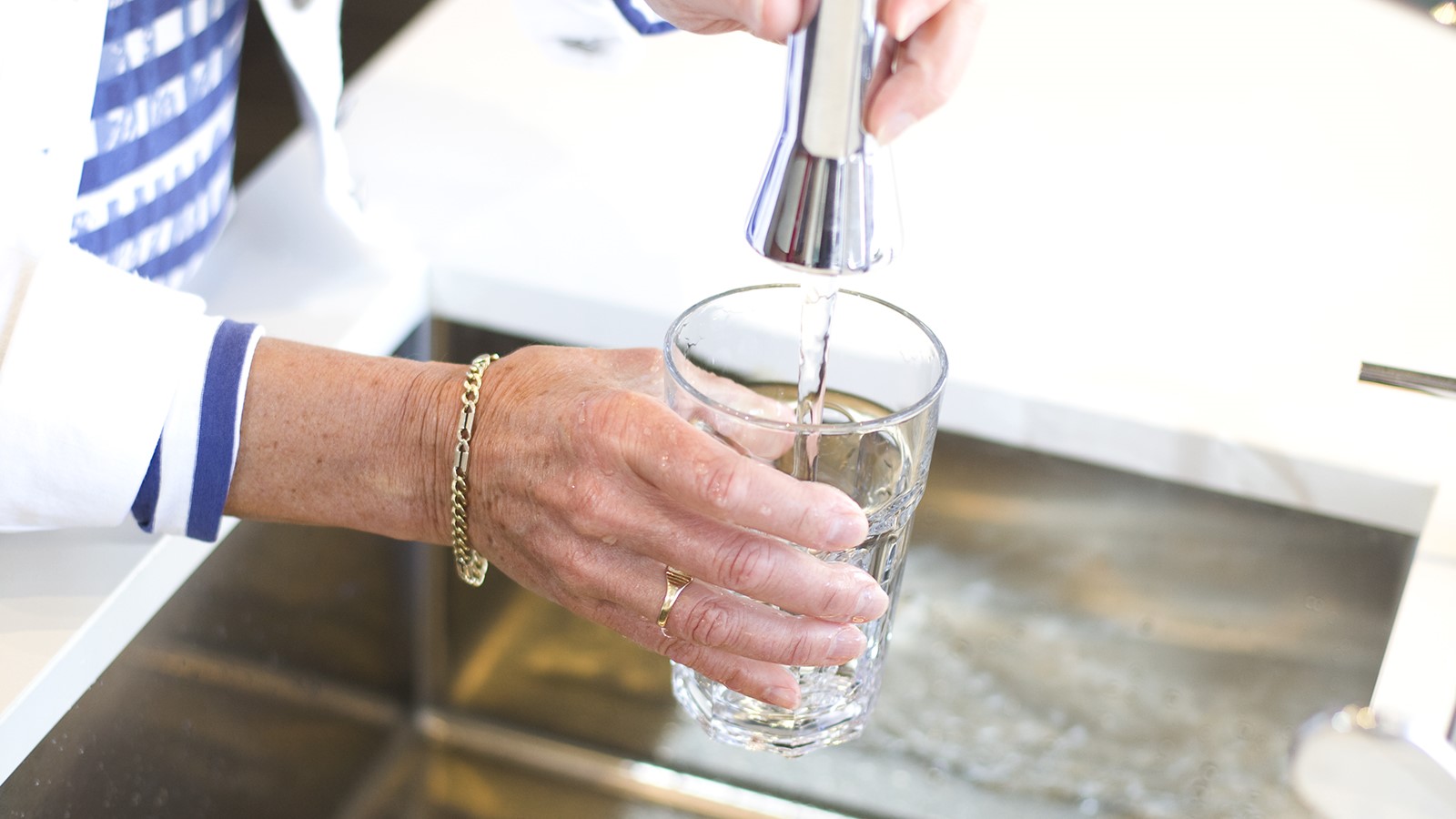 vrouwenhand tapt water in glas